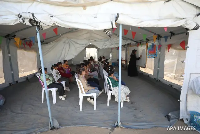Palestinian students attend a lesson inside a tent in al-Bureij camp in the central Gaza Strip on September 26, 2026, as the new academic year resumes. Classes are being held amid widespread damage to schools and shortag...
